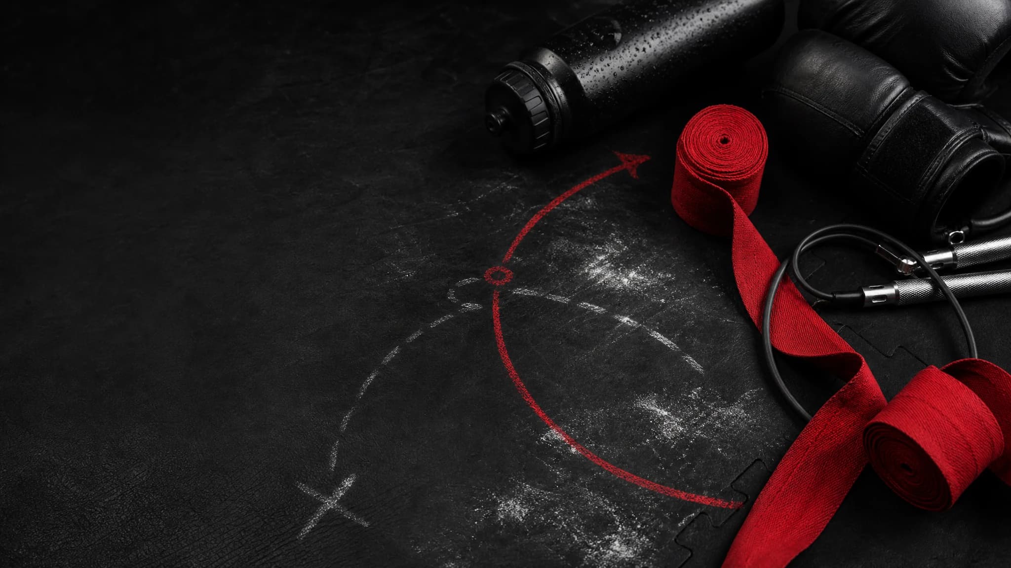 Rukavice, bandáže, švihadlo a křídové stopy pro první kickbox lekci bez lidí.