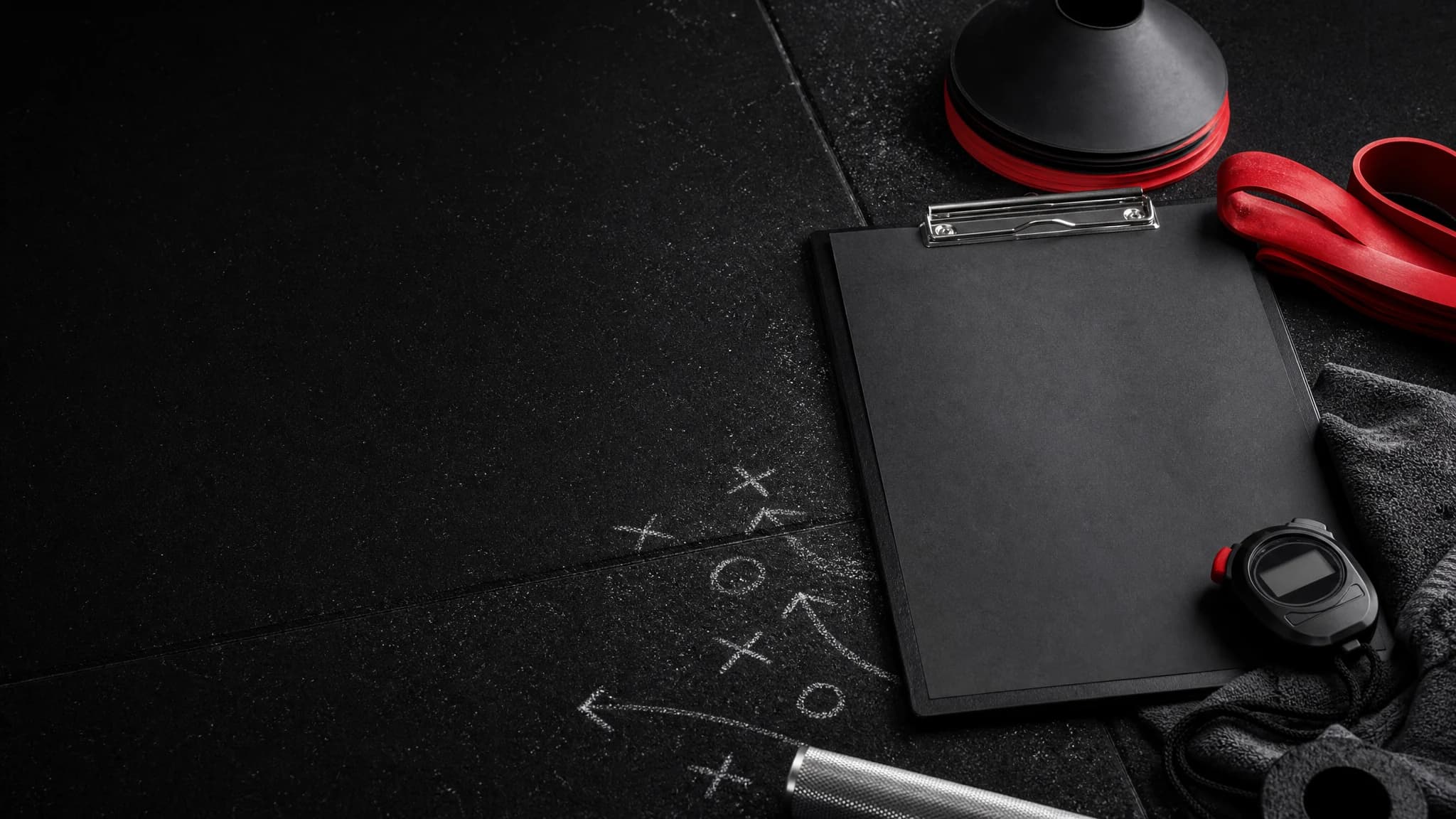 Tmavá trenérská hodnoticí stanice s prázdným clipboardem, kužely, stopkami a červeným pásem.